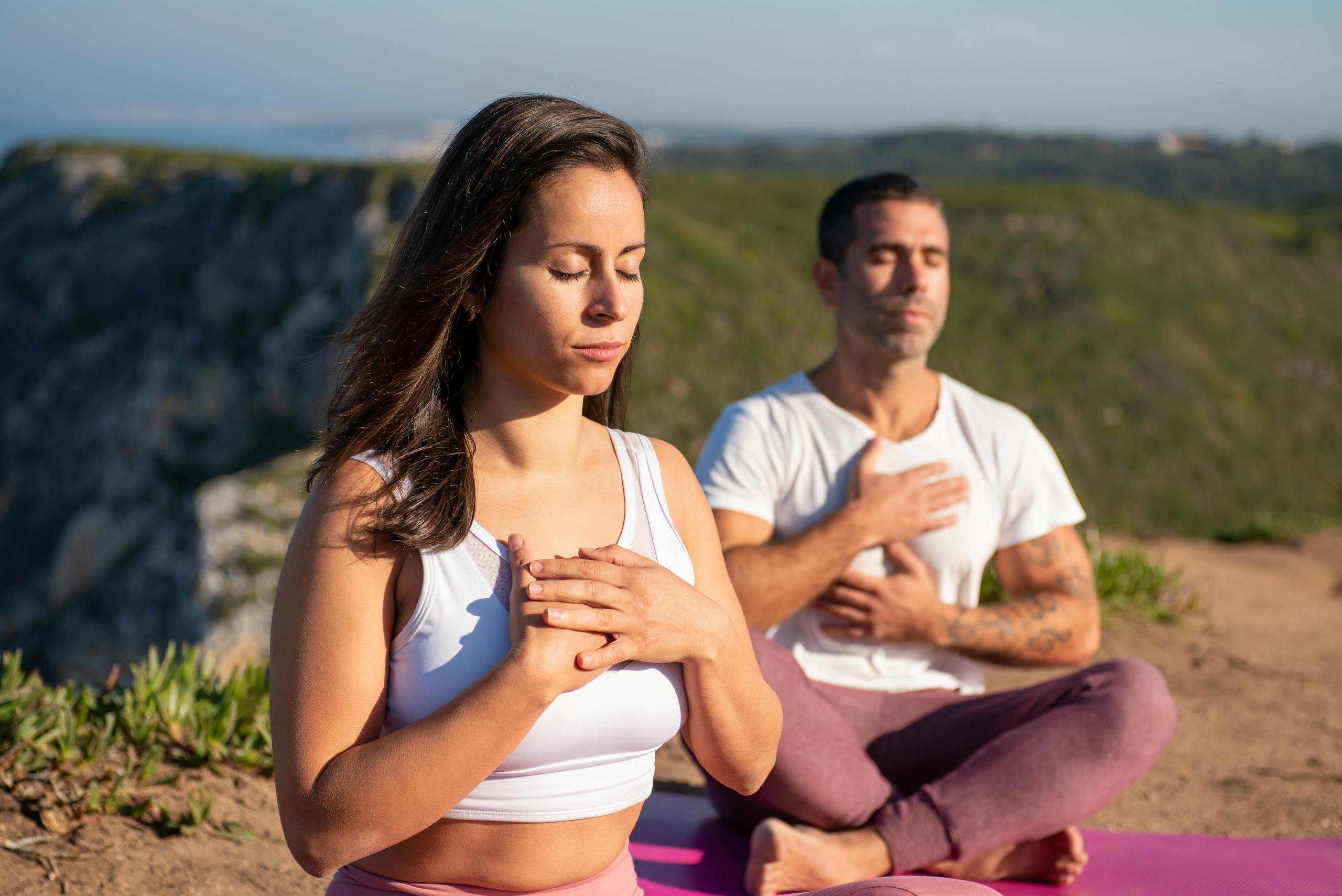 Two adults meditating outdoors in Portugal, embracing a serene yoga practice under the sun.